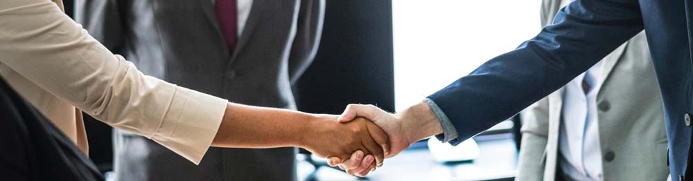 Two people shaking hands, with more people standing around them at Sandstone Creek Club, Hotel and Timeshares in Vail, Colorado